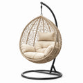 Sillón colgante de mimbre beige con estructura de acero y cojines de poliéster